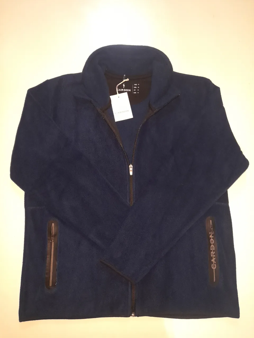Campera de micropolar azul marino con cuello alto y cierre completo. Posee dos bolsillos laterales con cierre y un detalle de logo estampado en uno de los laterales.