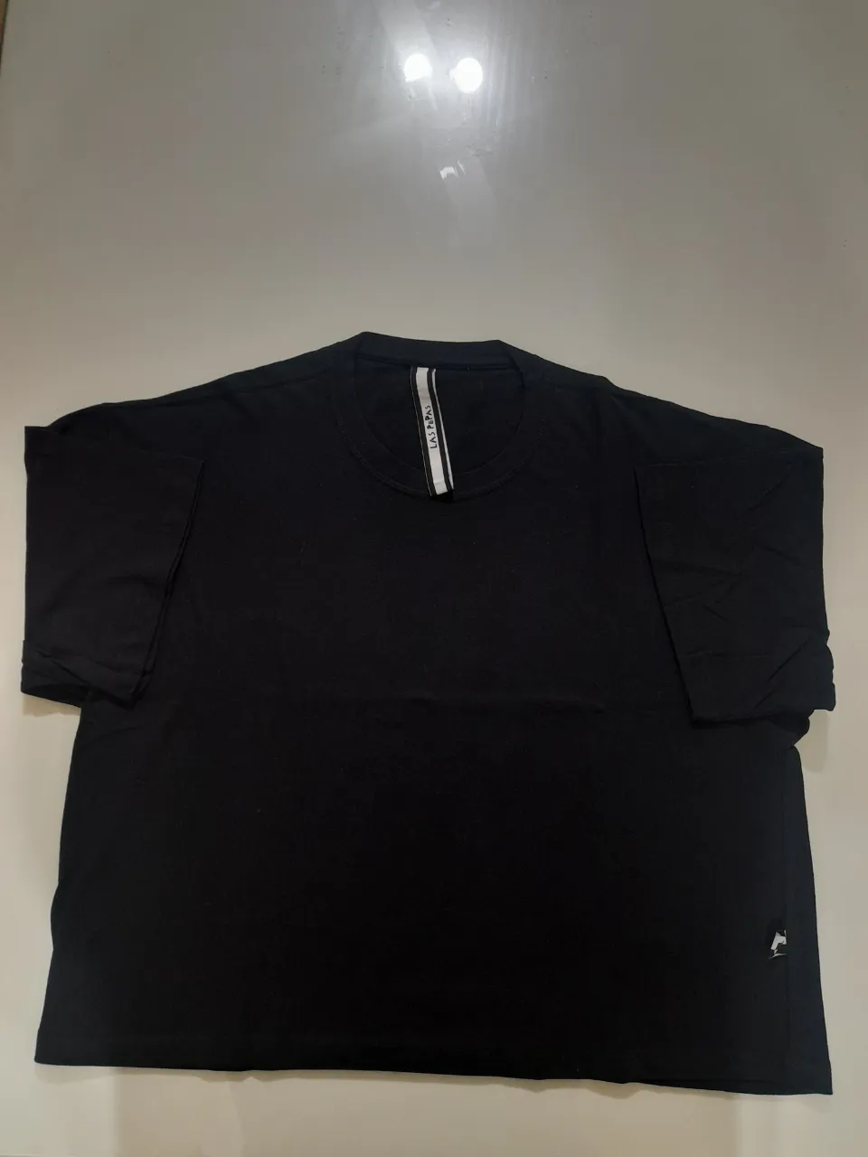 Remera negra de manga corta, con cuello redondo y detalle de etiqueta en la parte trasera. Ideal para un look casual y cómodo.