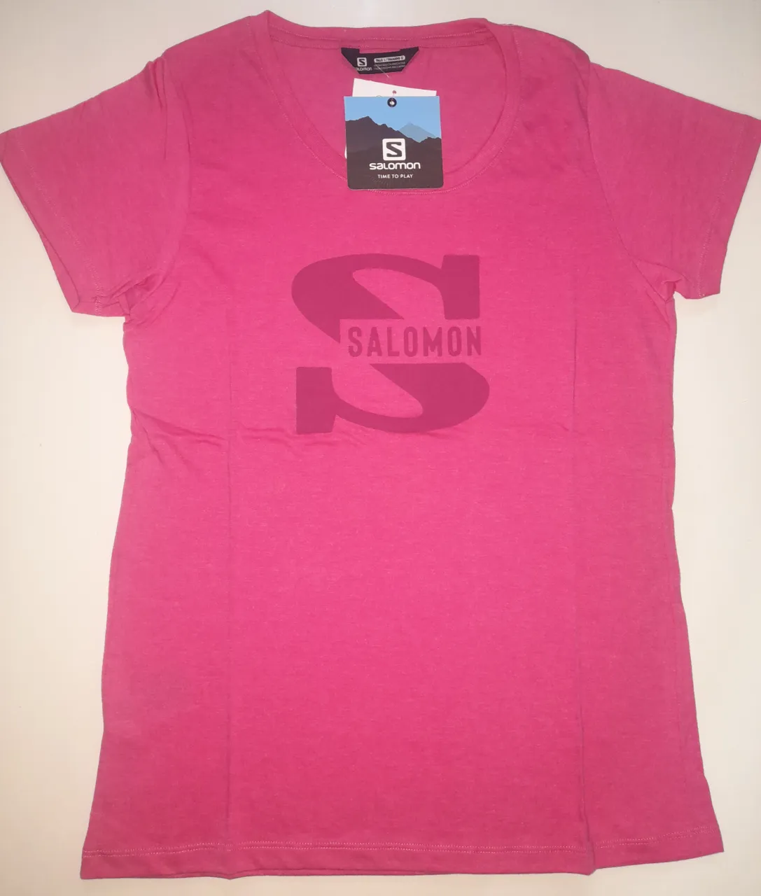 Remera deportiva de mujer Salomon, color rosa, con logo estampado. Talle L. Ideal para actividades al aire libre.