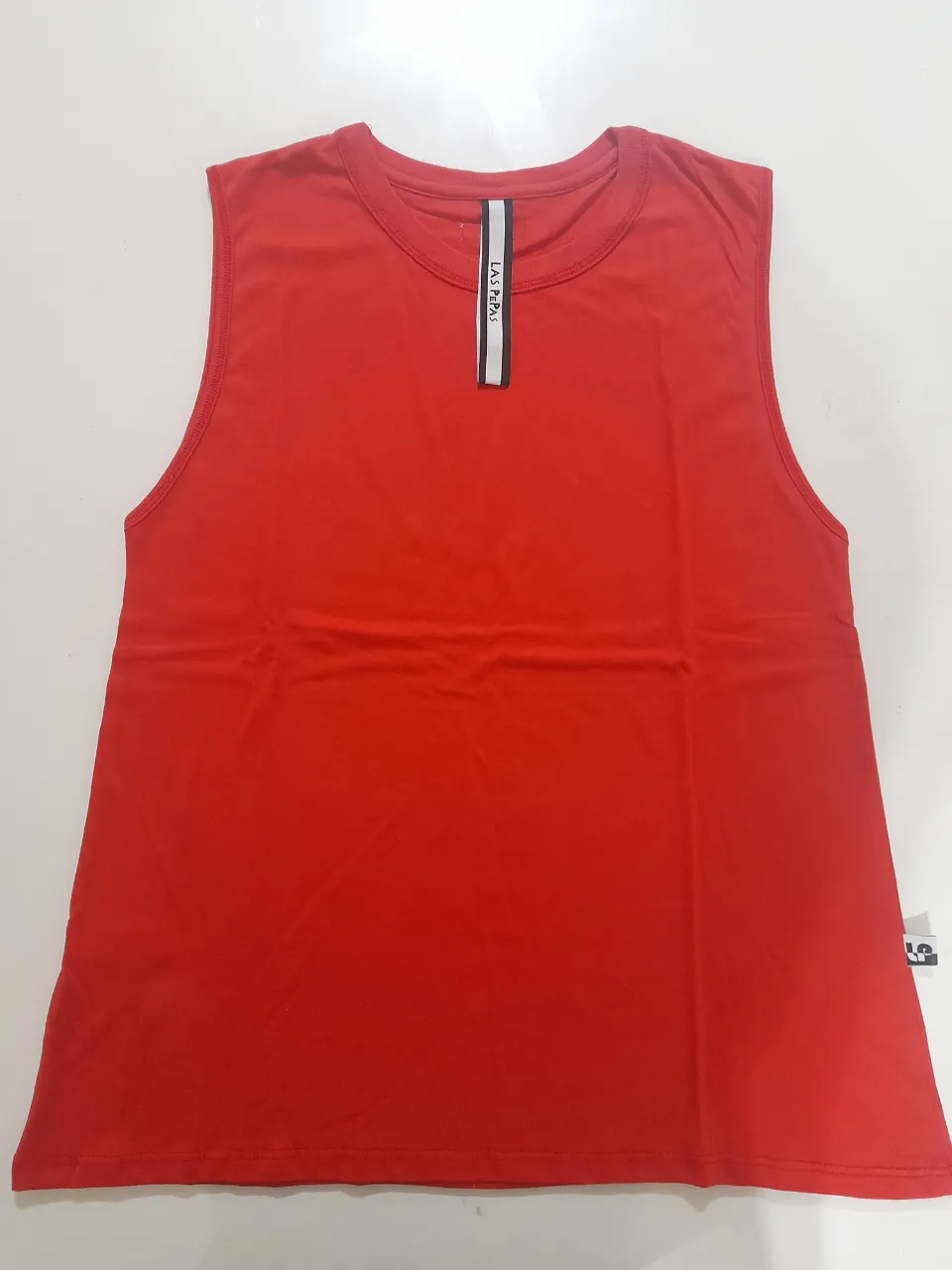 Musculosa roja de mujer, sin mangas, con detalle de cinta en el cuello con la marca LAS PEPAS. Ideal para entrenar o usar en el día a día.