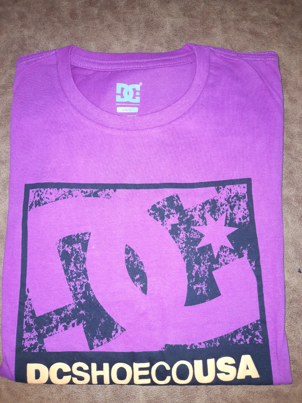 Remera de hombre DC color violeta con estampado del logo de la marca en el frente. Ideal para un look casual y urbano.