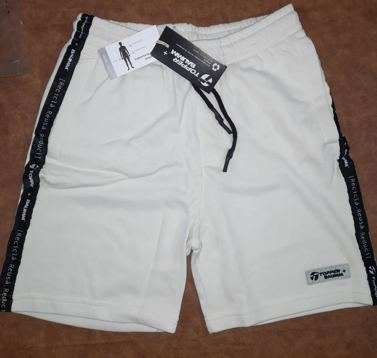 Short deportivo color crudo. Unisex, con detalles en negro y logo de la marca. Ideal para actividades físicas y uso casual.