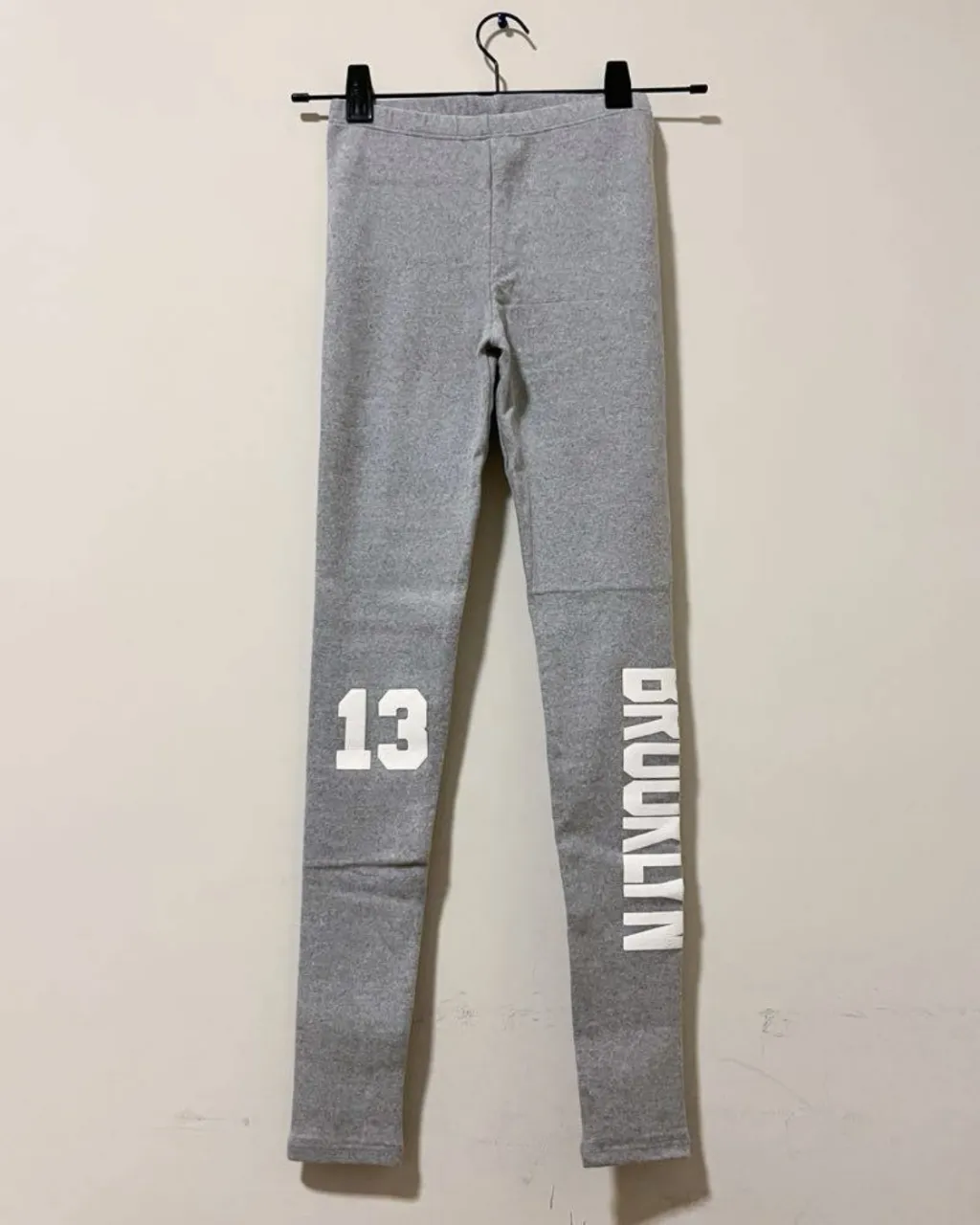 Calza gris con estampa de número "13" en la pierna izquierda y la palabra "BROOKLYN" en la pierna derecha. Ideal para un look urbano y deportivo.