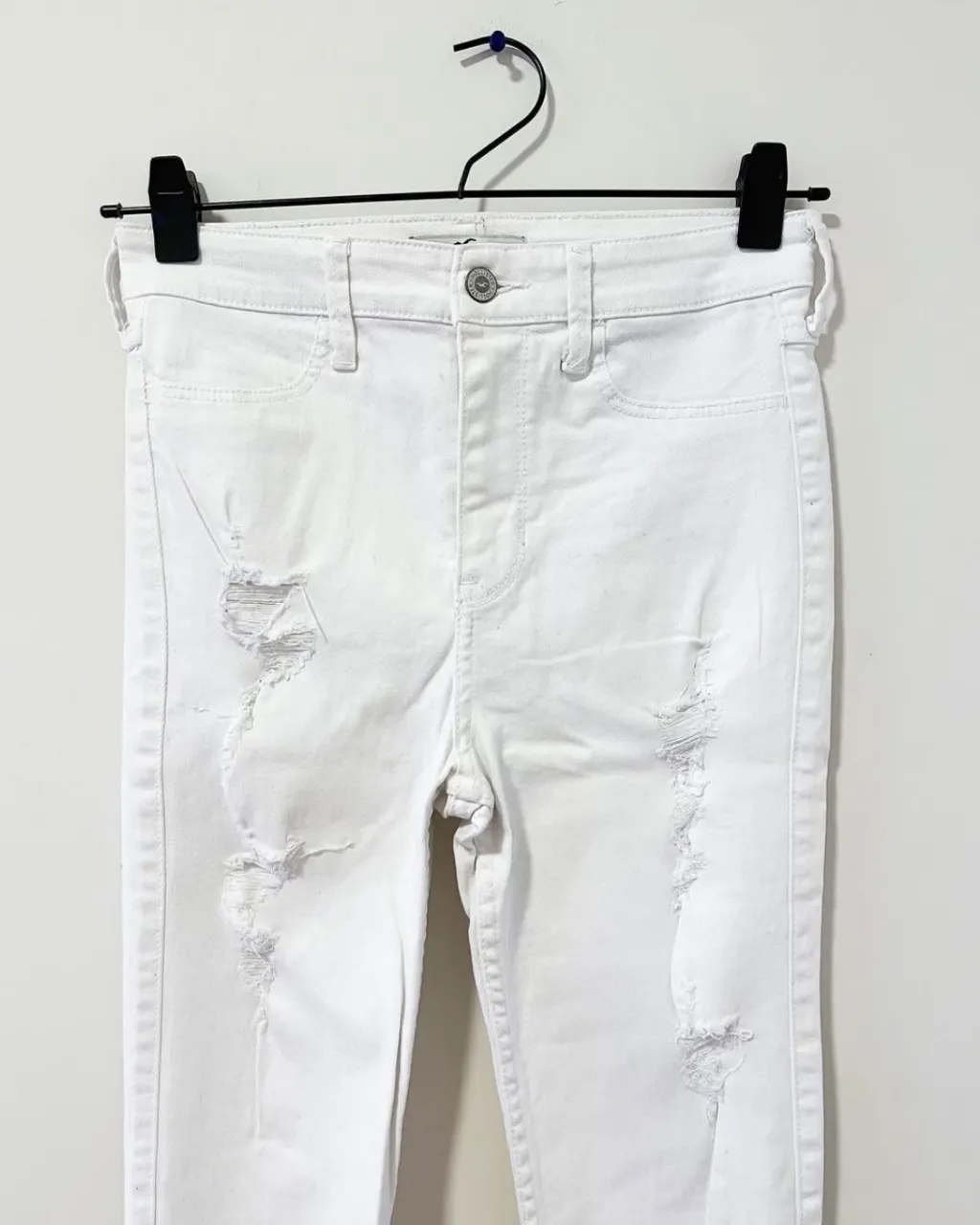 Jeans blancos tiro alto con roturas y detalles desflecados en los tobillos. Un básico canchero para looks de día o noche.