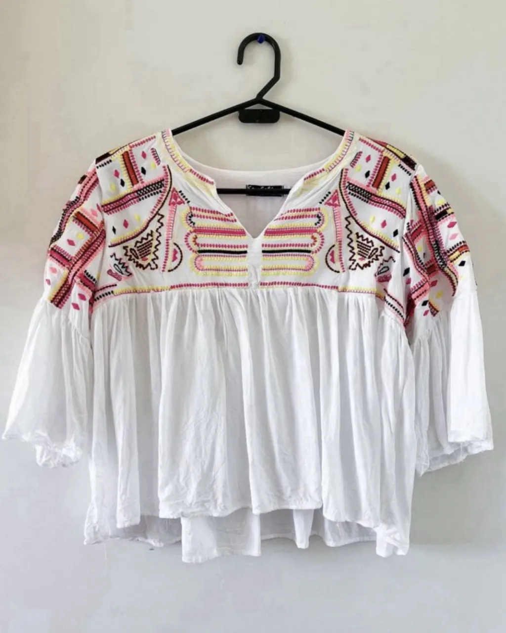 Blusa blanca con bordados coloridos en el cuello y mangas. Posee mangas acampanadas y un corte holgado que la hace súper cómoda y canchera. Ideal para un look boho chic.