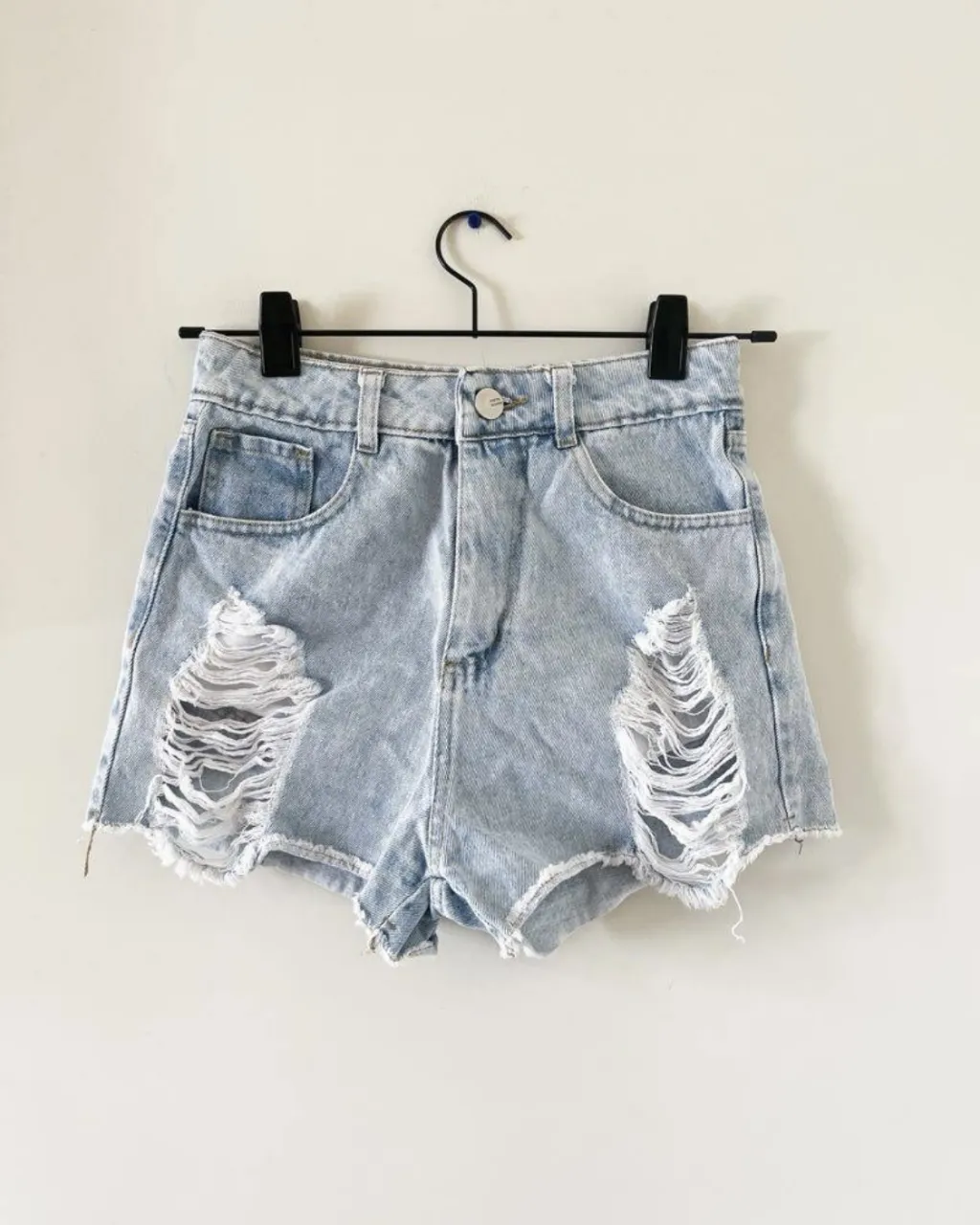 Shorts de jean tiro alto, súper modernos y cancheros. Tienen roturas desgastadas en el frente y un corte desflecado en la parte inferior. Ideales para un look relajado y a la moda.