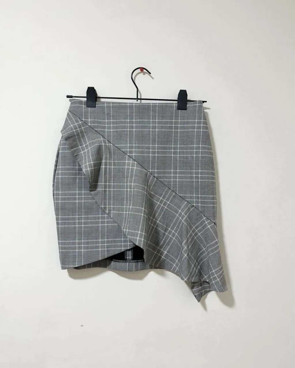 Pollera gris a cuadros con diseño asimétrico y corte moderno. Ideal para un look canchero y con onda.