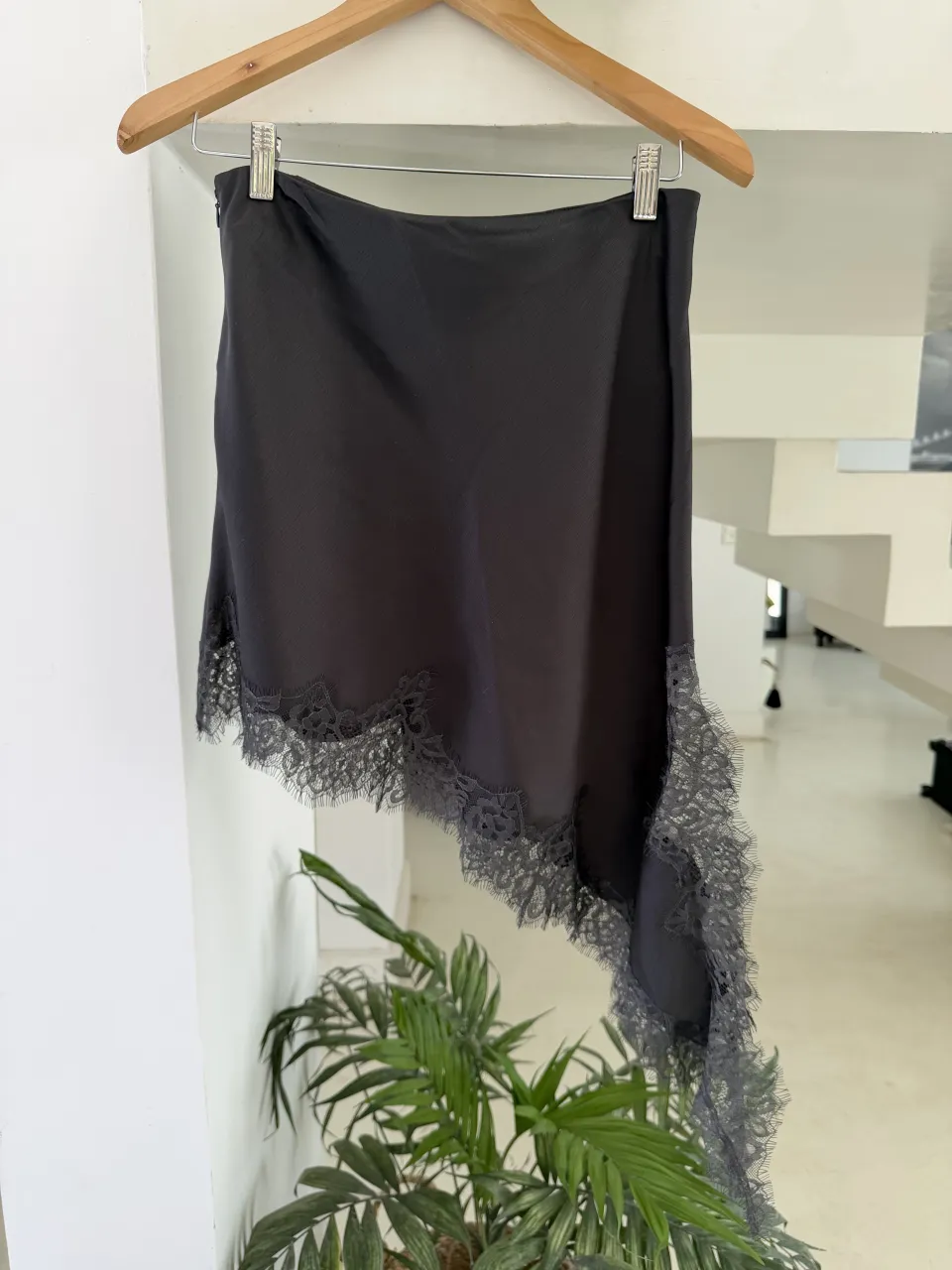 Pollera corta gris con detalles de encaje en el borde inferior y en un lateral. La pollera tiene un corte asimétrico.