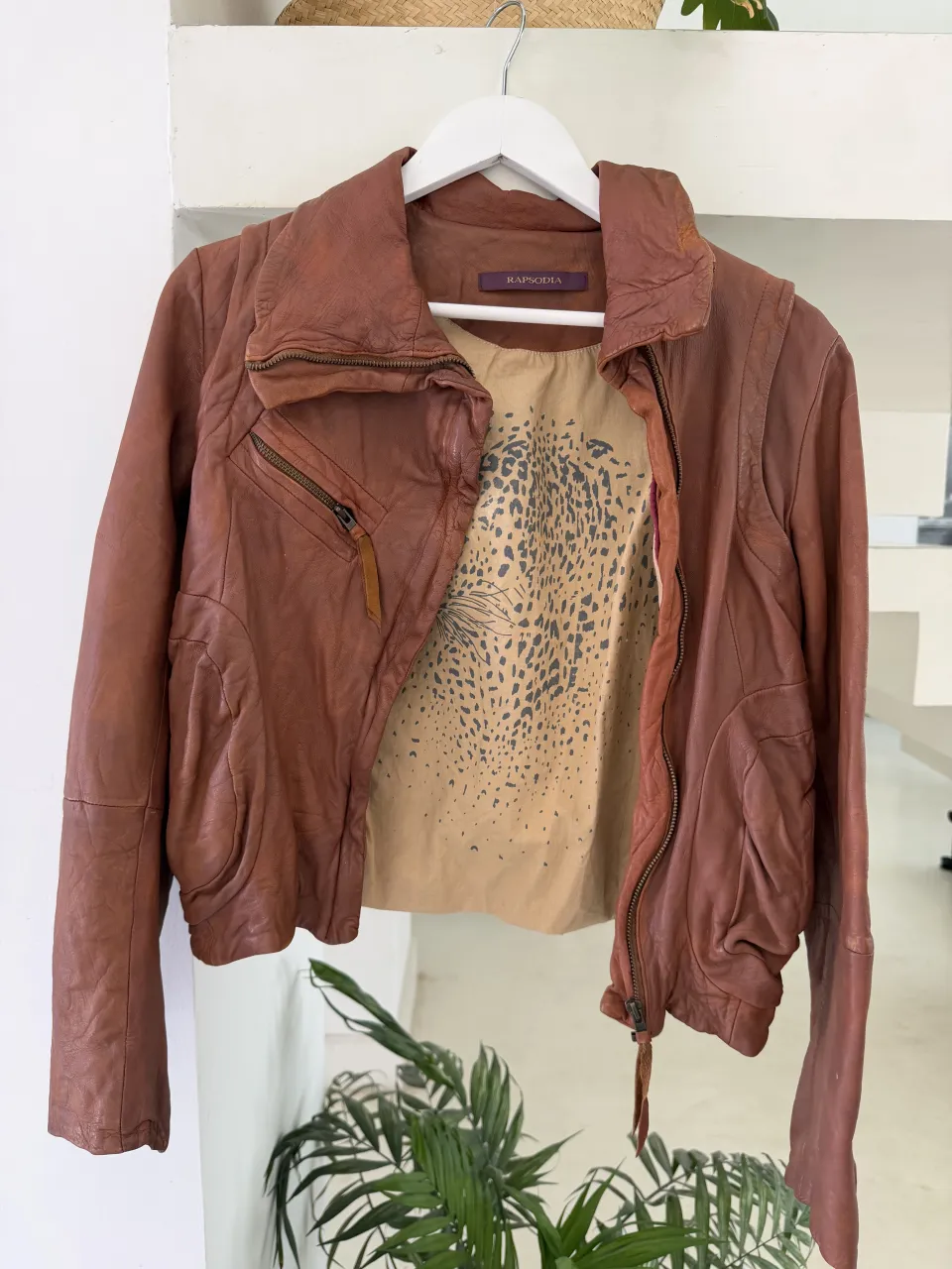 Campera de cuero marrón. Posee dos bolsillos frontales con cierre y detalle de tiras de cuero.