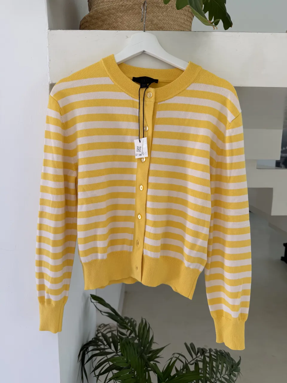 Cardigan a rayas amarillas y blancas, con botones delanteros y cuello redondo.