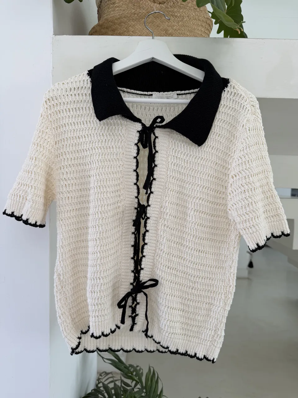 Remera Zara de tejido de punto blanco con cuello y puños negros. Posee detalles de puntilla negra en el frente y en los bordes de las mangas y el ruedo. Se ata con cordones negros en el escote.