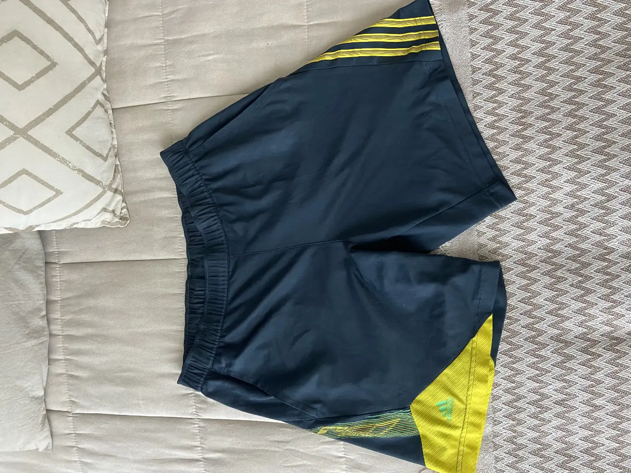Short deportivo Adidas de hombre, color azul marino con detalles en amarillo. Ideal para entrenamientos y actividades físicas. Talle M.