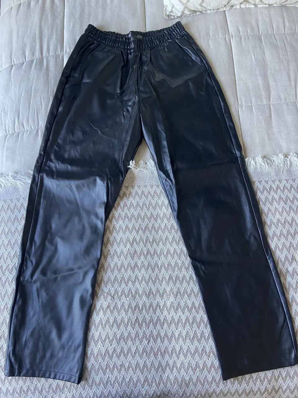 Pantalón de cuero sintético negro, con cintura elastizada y corte recto. Ideal para un look moderno y versátil.       Talle M