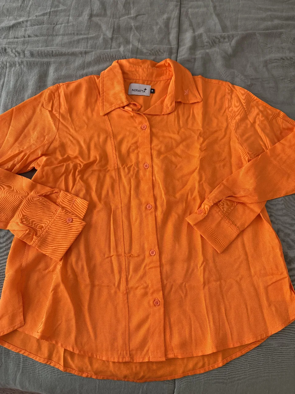 Camisa naranja vibrante, ideal para darle un toque de color a tu outfit. Con botones al frente y cuello clásico, perfecta para un look casual o más arreglado. Su diseño moderno la hace versátil para distintas ocasiones.