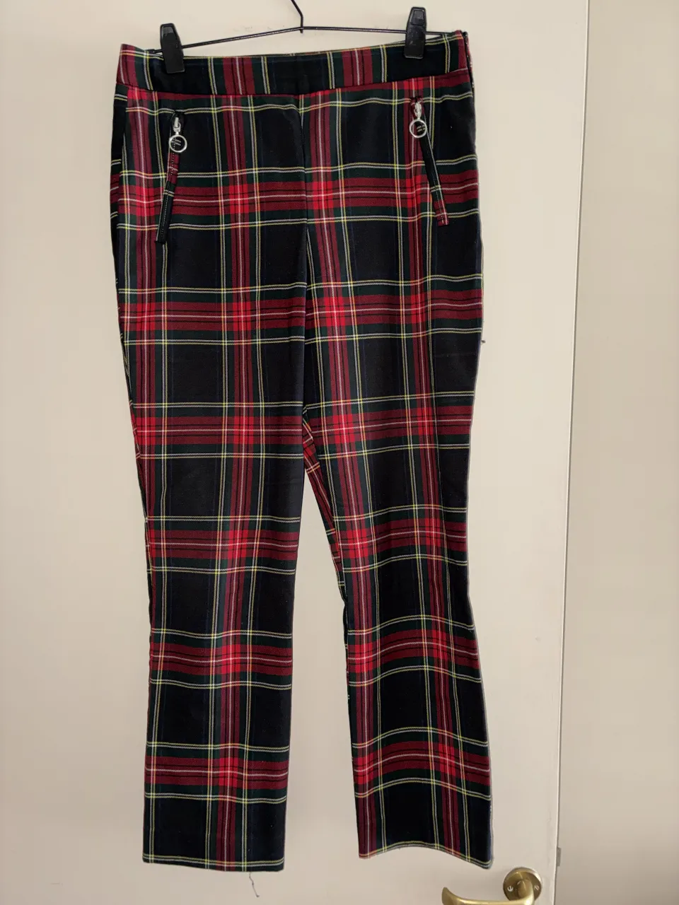 Pantalón de cuadros escoceses en rojo, verde, amarillo y negro. Posee bolsillos delanteros con cierre y bolsillos traseros.