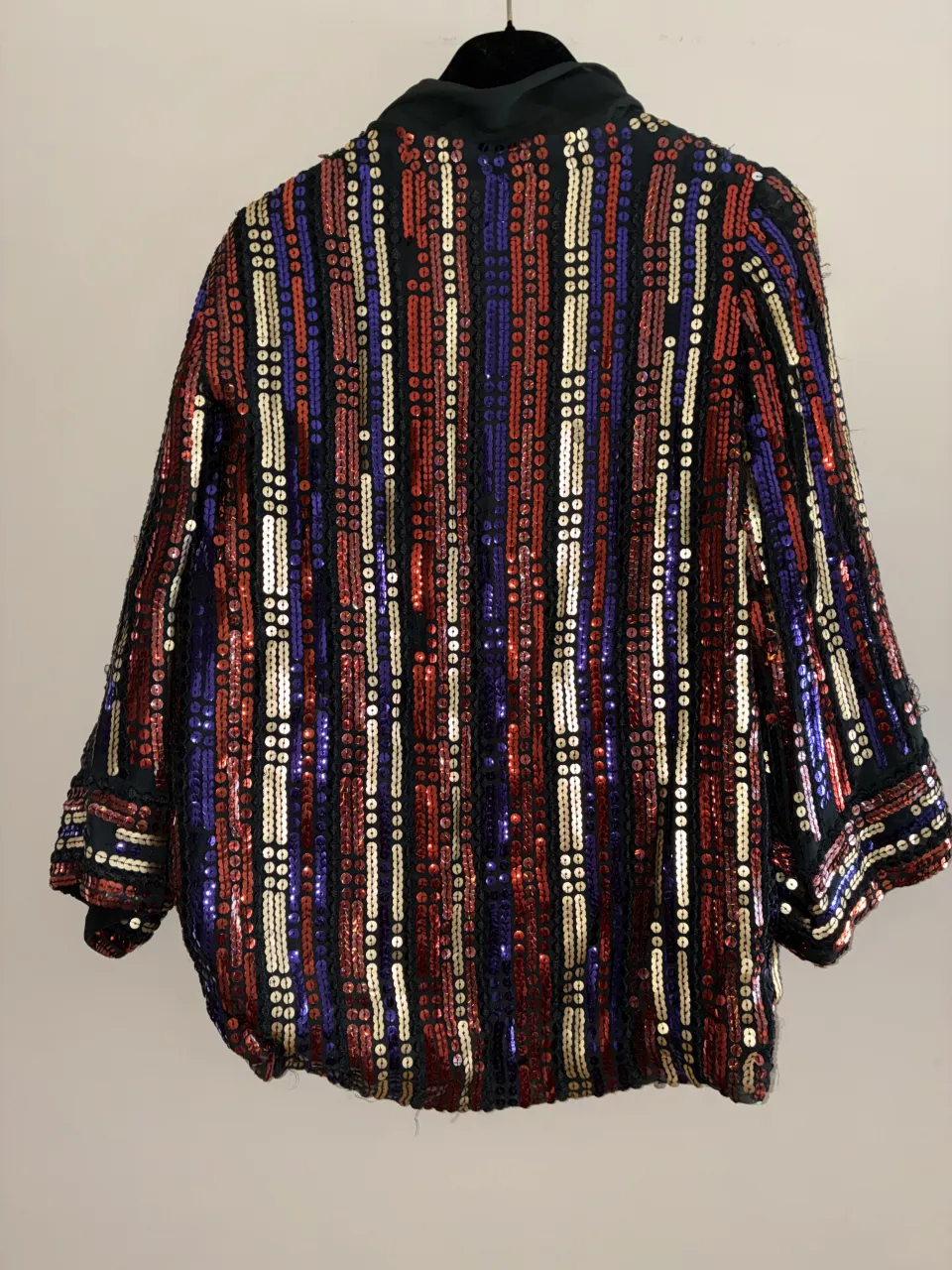 Campera con lentejuelas multicolores en franjas verticales. Cuello solapa. Mangas largas.