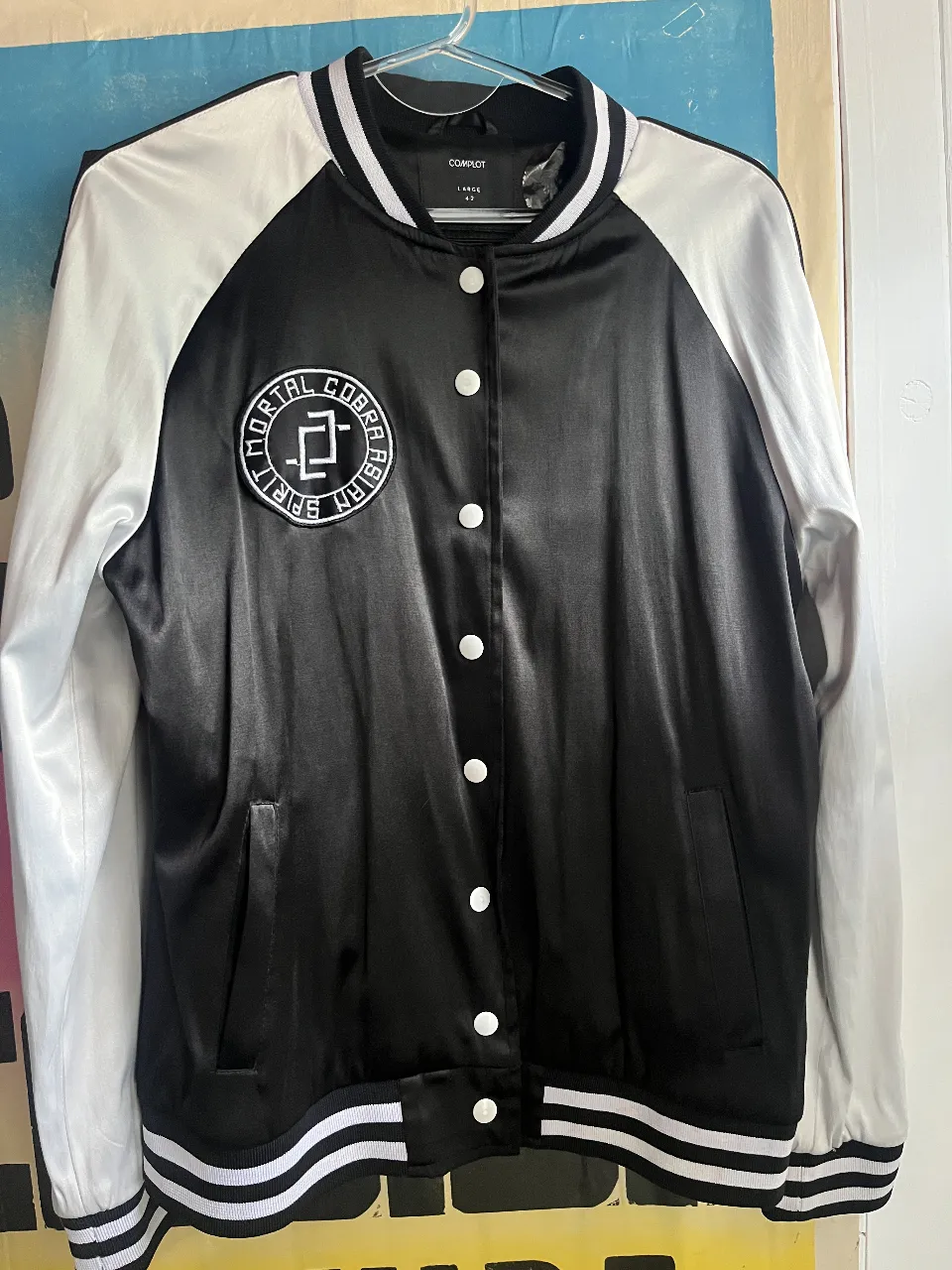 Campera bomber negra con mangas blancas y bordado de cobra en la espalda. Ideal para un look urbano y canchero.