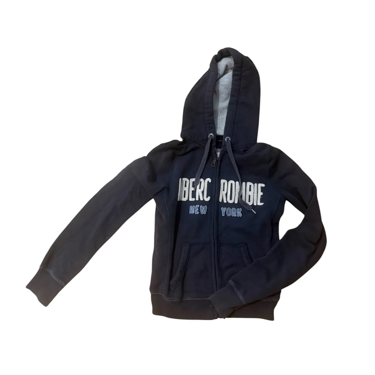 Buzo azul marino con capucha y cierre completo. Estampado de letras blancas y celestes en el frente que dice "ABERCROMBIE NEW YORK".