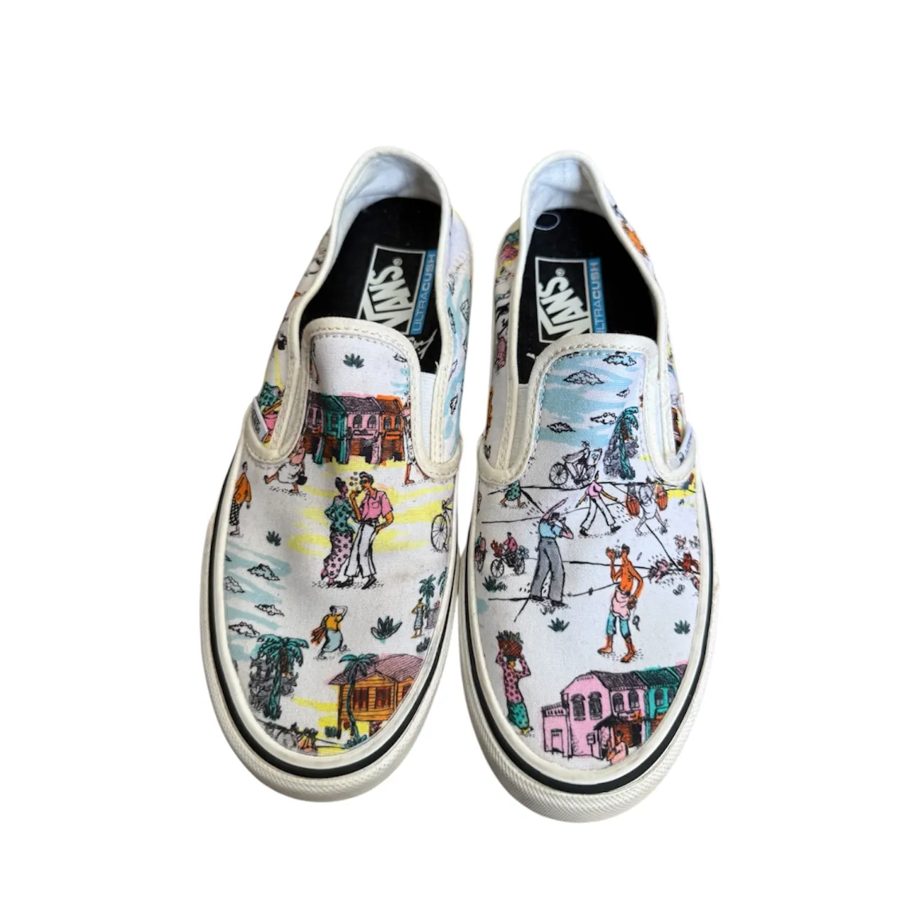 Zapatillas Vans slip-on con estampa de escenas veraniegas y personajes. Diseño multicolor sobre base blanca.