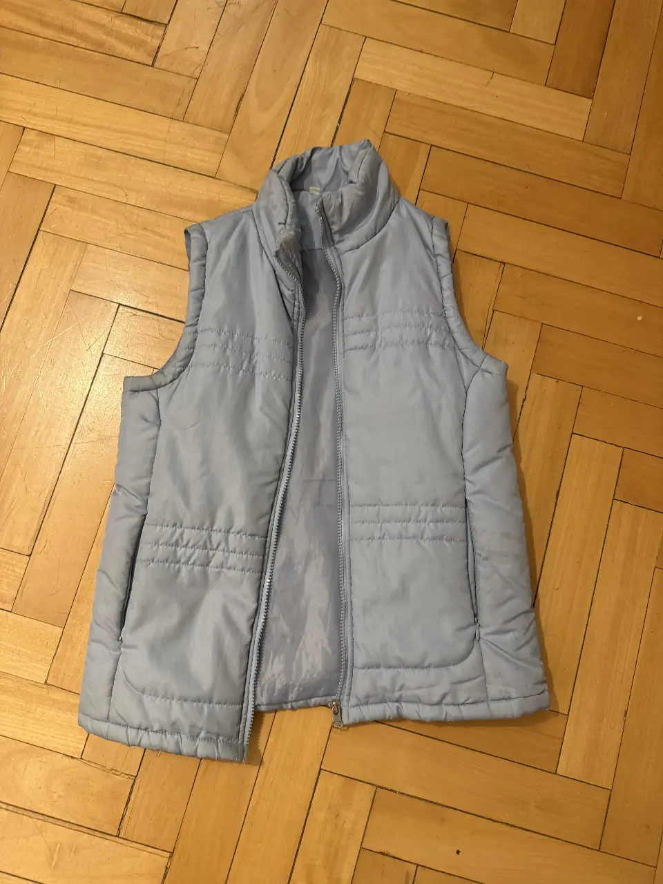 Chaleco acolchado celeste, ideal para usar sobre otras prendas en días frescos. Cuenta con cierre y bolsillos.