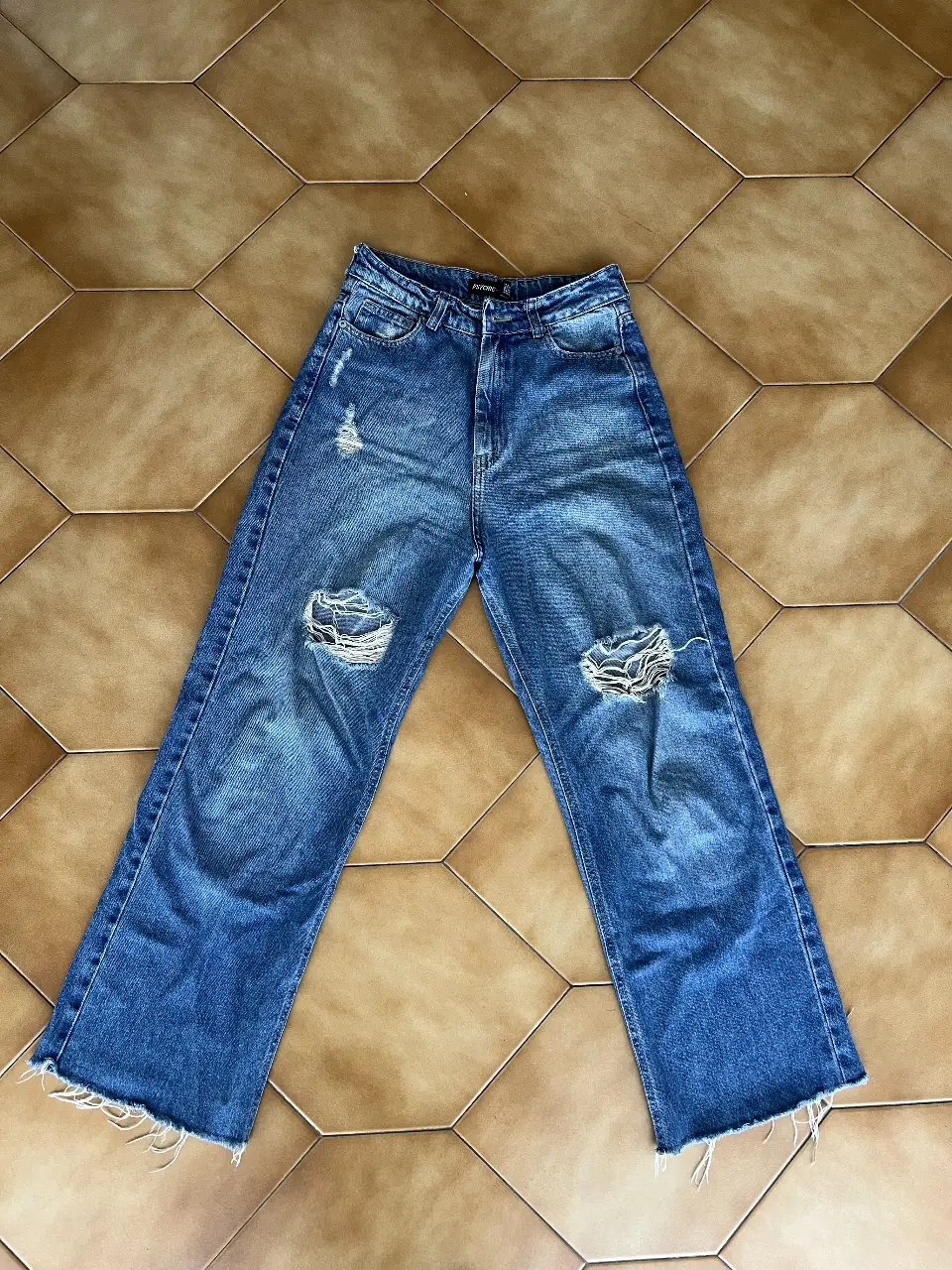 Jeans de mujer, tiro alto, con roturas en las rodillas. Corte wide leg y desflecado en el bajo. Ideal para un look casual y moderno.