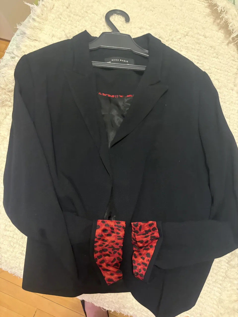 Blazer negro con detalles de estampado animal print en rojo y negro en los puños y en el interior.