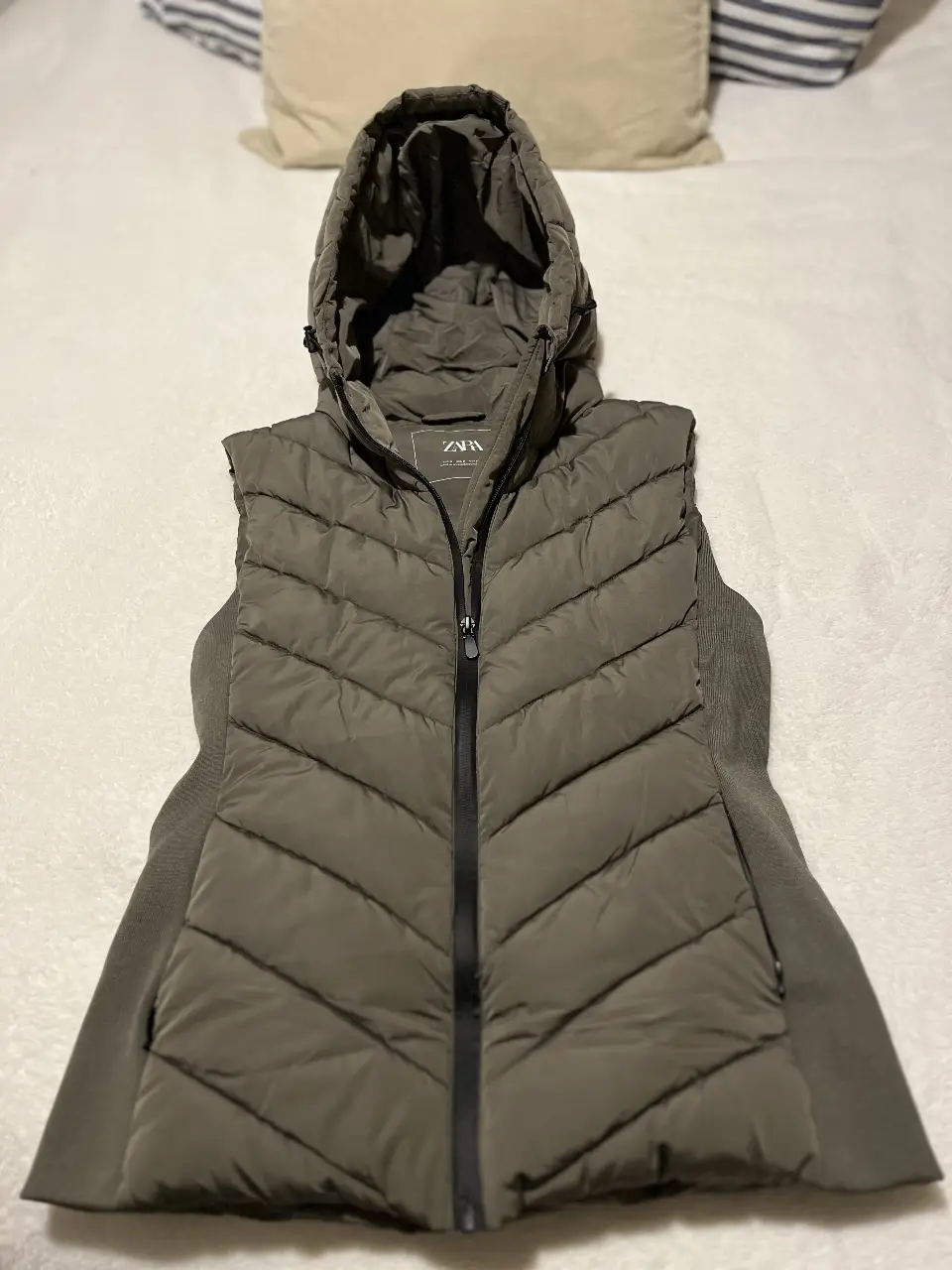 Chaleco puffer con capucha para mujer, color gris. Ideal para el invierno, con cierre frontal y detalles acolchados. Marca Zara.