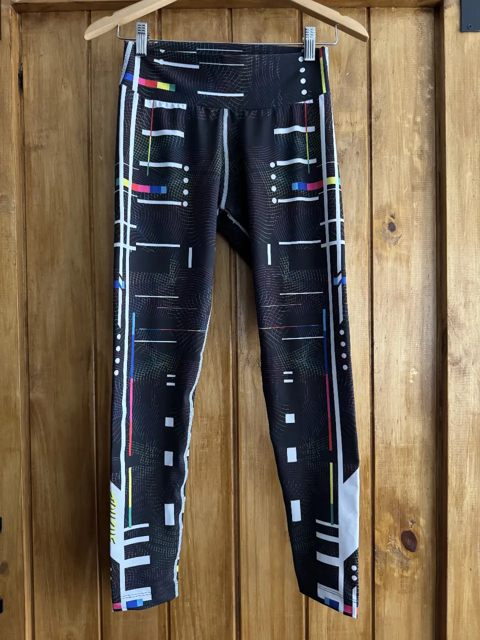 Calzas deportivas negras con diseño geométrico y detalles en blanco, rojo, amarillo y azul. Perfectas para entrenar con estilo.