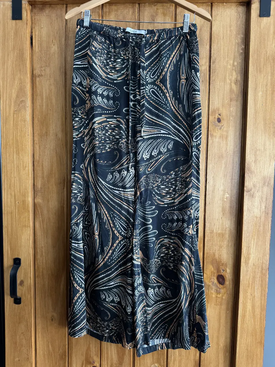 Pantalón suelto de mujer con estampado paisley en tonos negro, dorado y blanco. Ideal para un look boho chic.