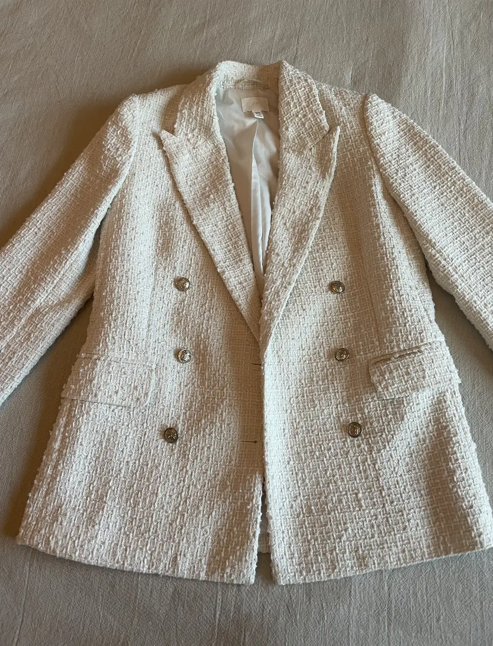 Blazer Off white de tweed, con botones dorados y corte entallado. Es de H&M y está nuevo sin uso. Talle equivale a un Small. Largo total 65 cm. Medida sisa a sisa es de 45 cm. (Ideal hasta 90 cm de busto) 