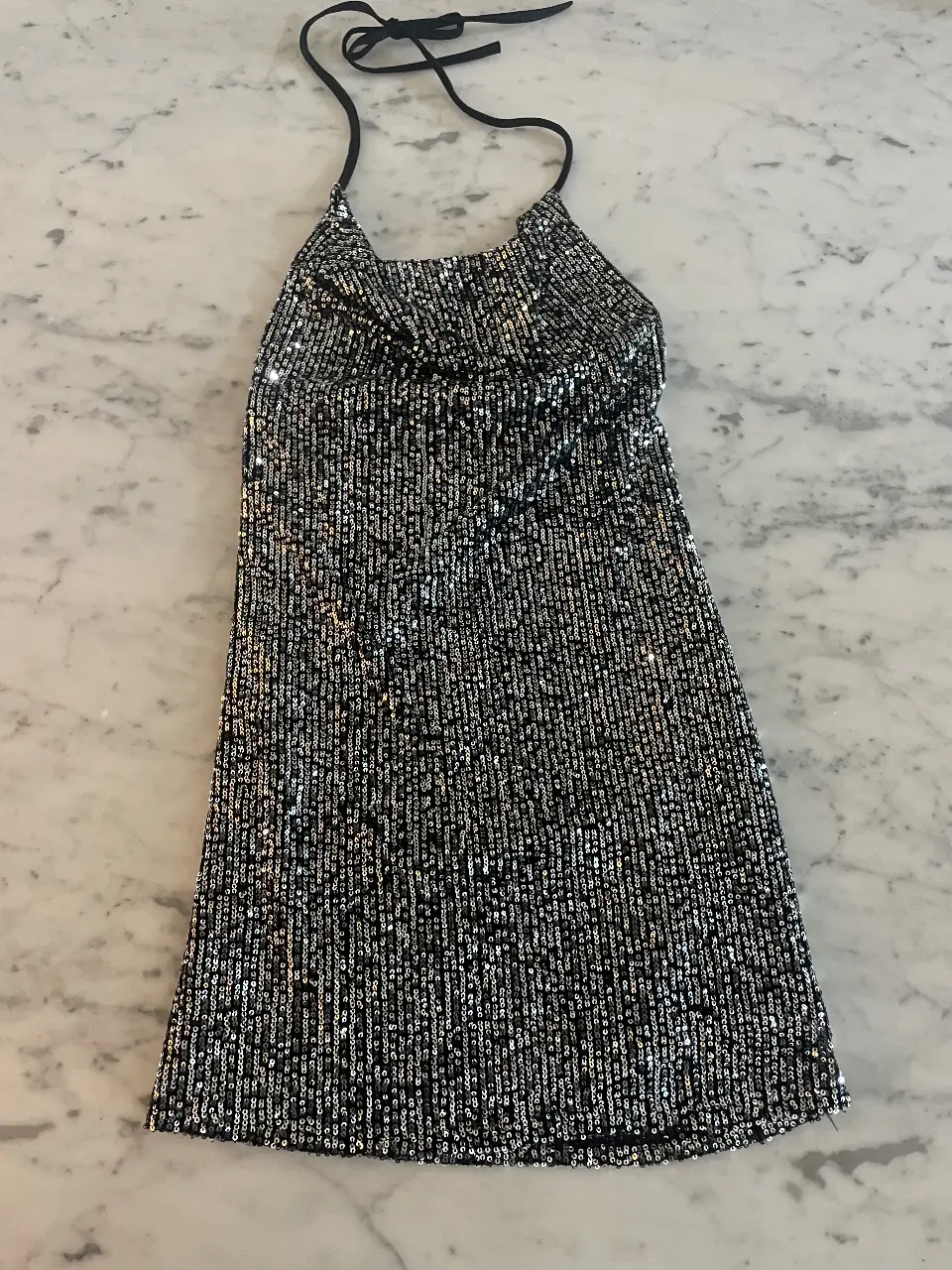 Vestido mini al cuerpo de lentejuelas plateadas. escote buche  con espalda descubierta. Talle XS