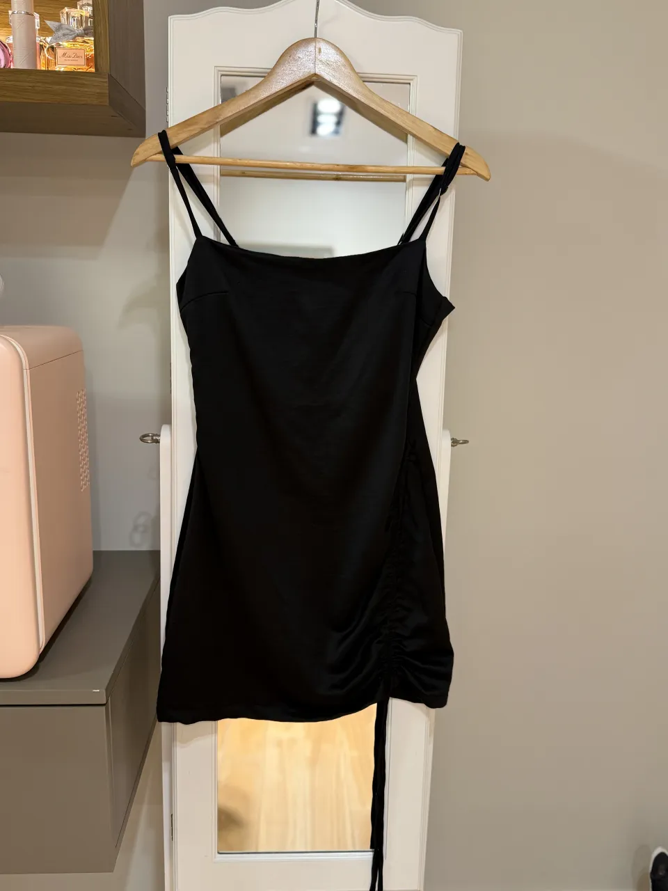 Vestido negro con tiras finas y detalle de fruncido con lazo en un lateral.