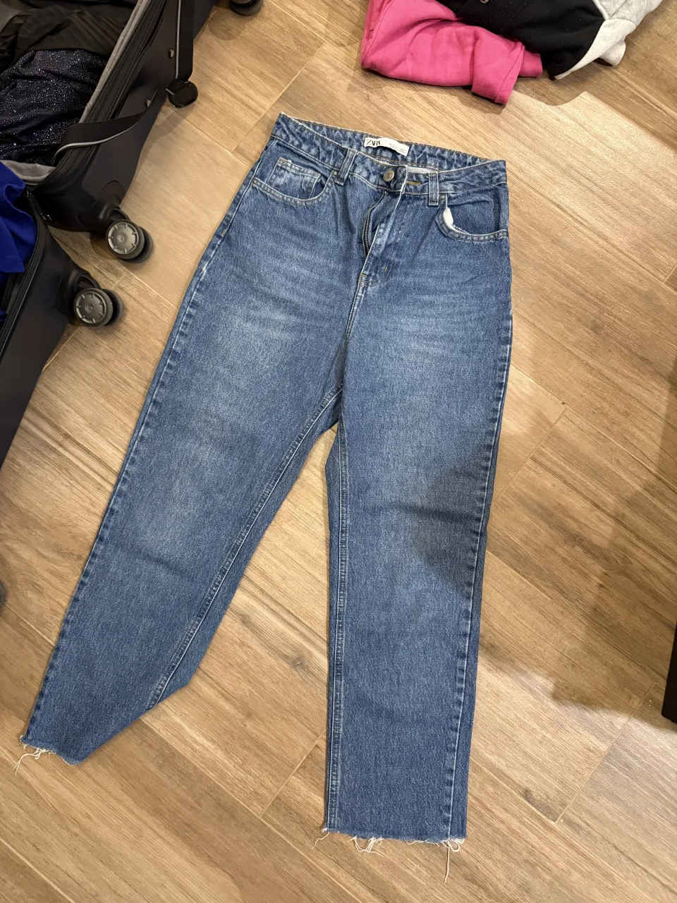 Jeans de tiro alto con roturas y detalles deshilachados en los bajos. Cierre con botón.