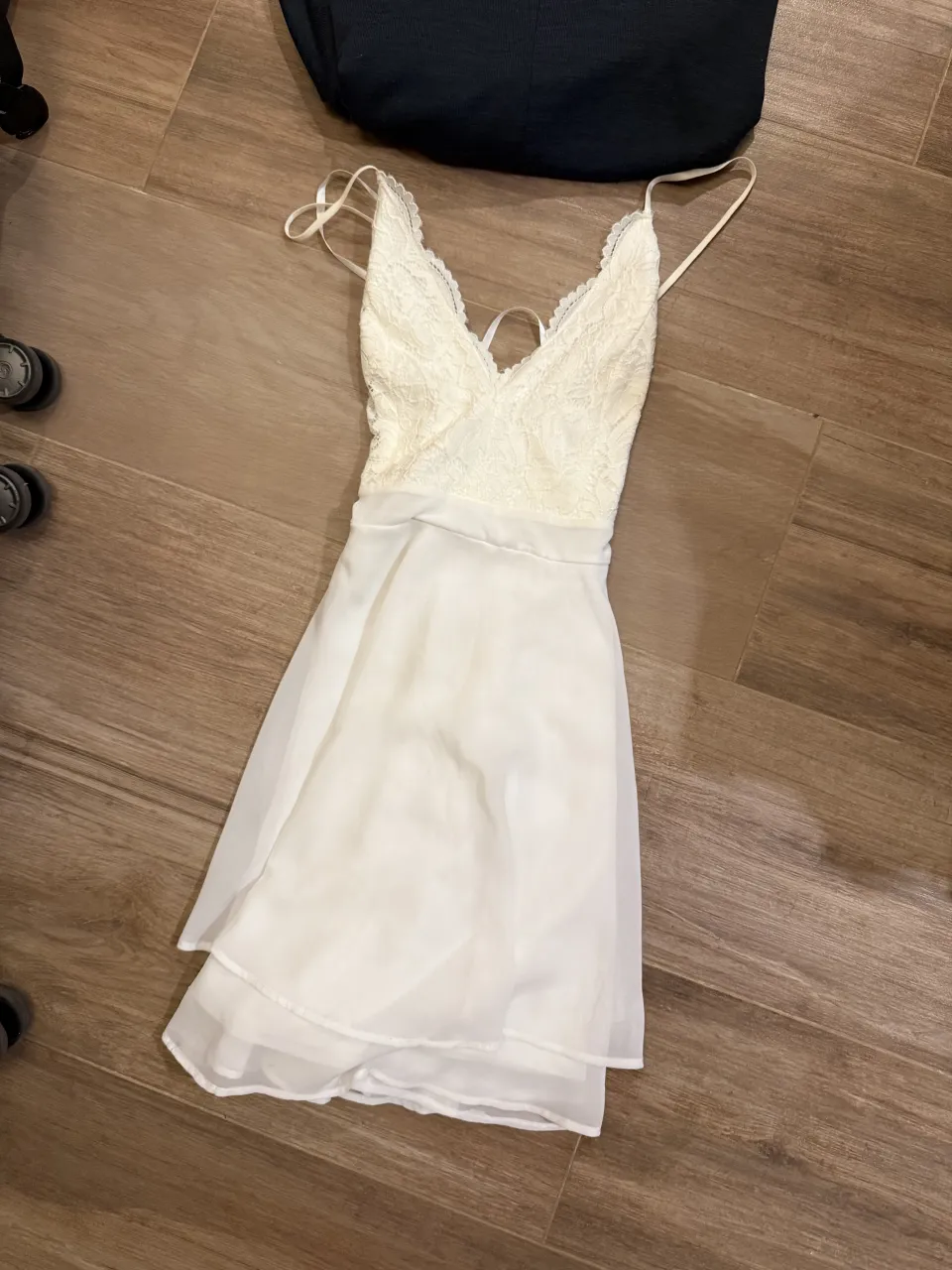 Vestido blanco con breteles finos y escote en V. La parte superior es de encaje y la falda es de tela vaporosa con dos capas.