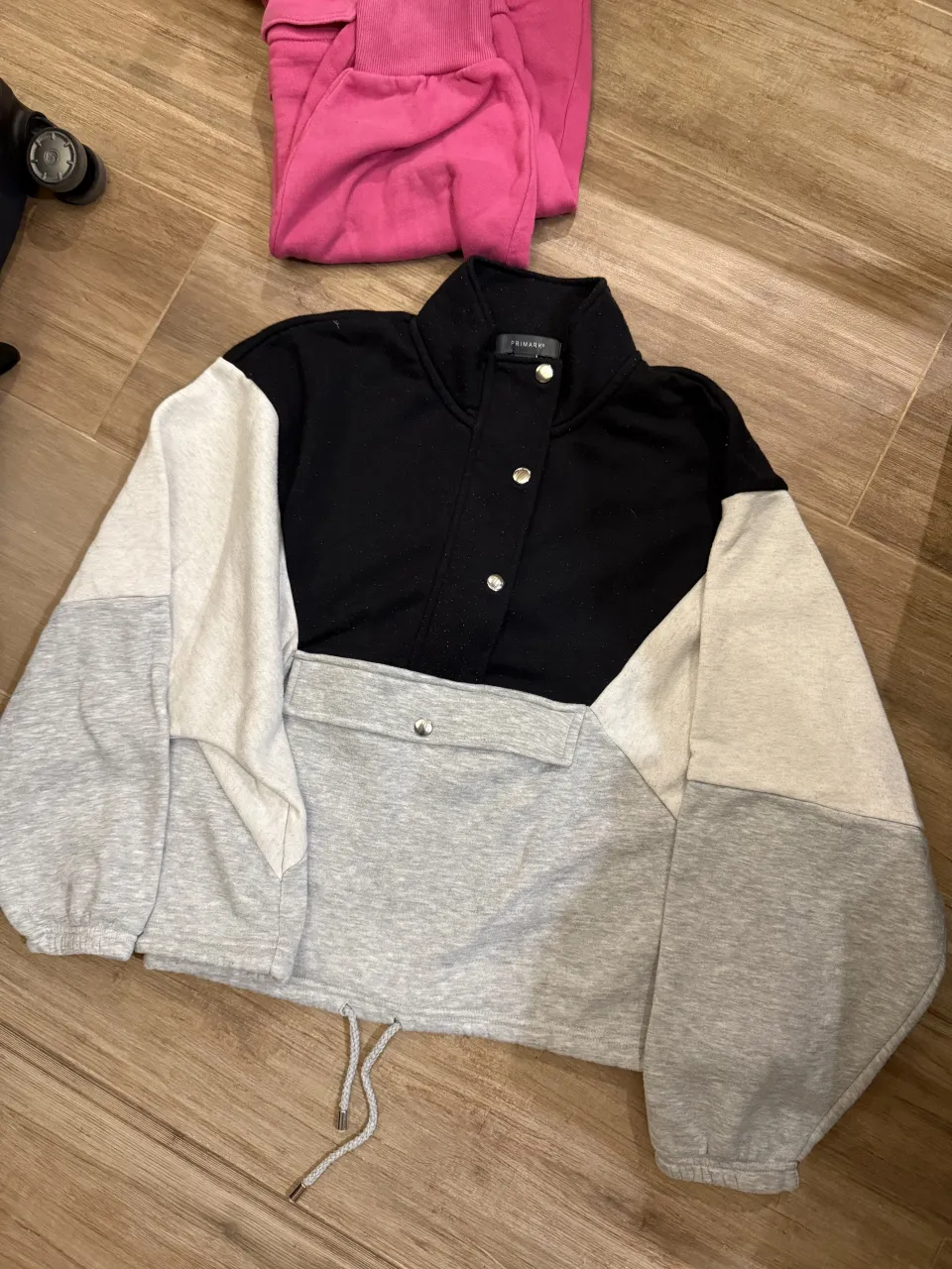 Buzo de friza con cuello alto y cierre. Posee bolsillos frontales con tapa y botones a presión. Mangas largas con puños elastizados. Cordón ajustable en la cintura. Con pelotitas