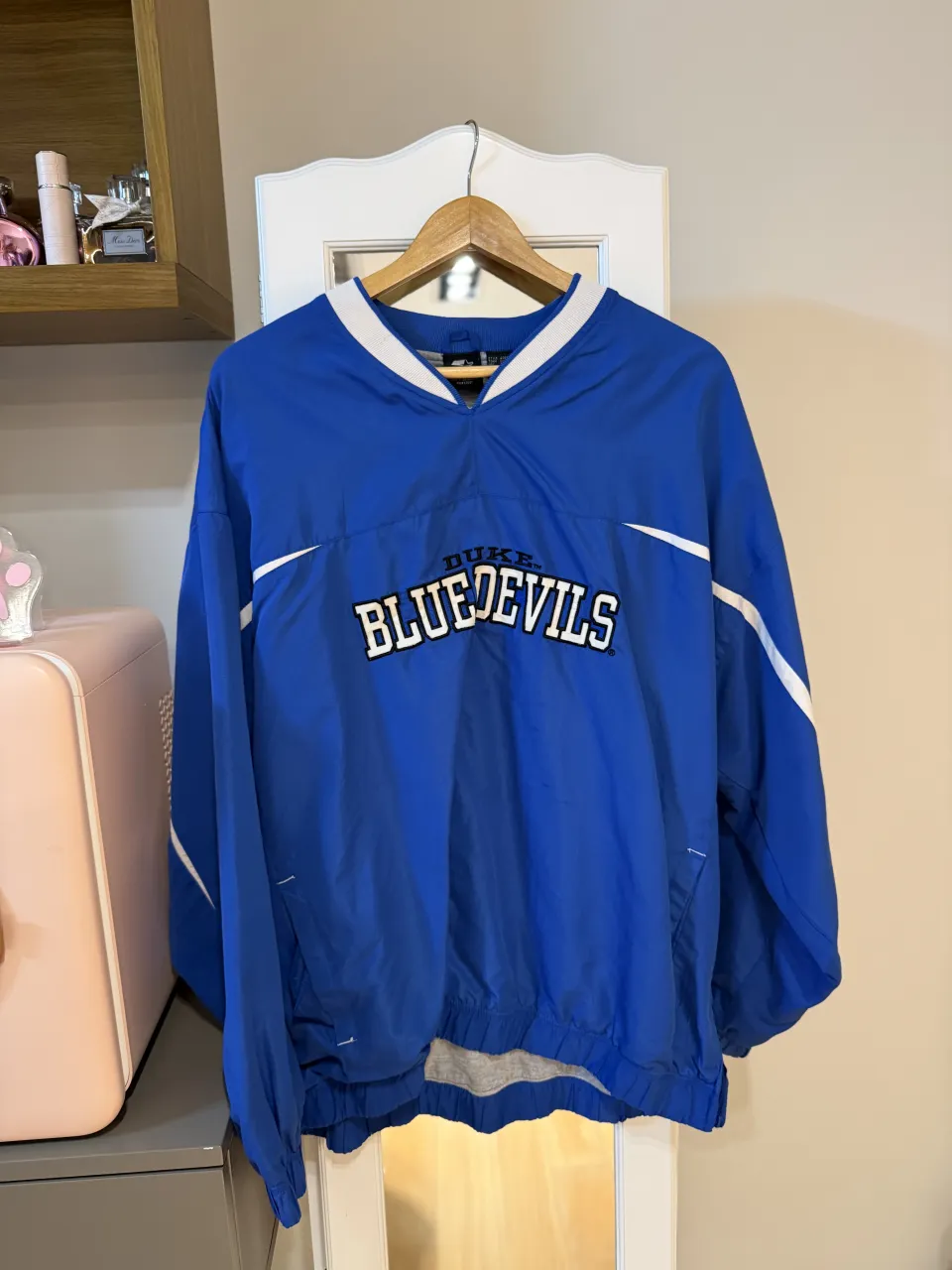 Campera deportiva azul con cuello en V y detalles blancos en los hombros. Estampa "DUKE BLUE DEVILS" en el frente.