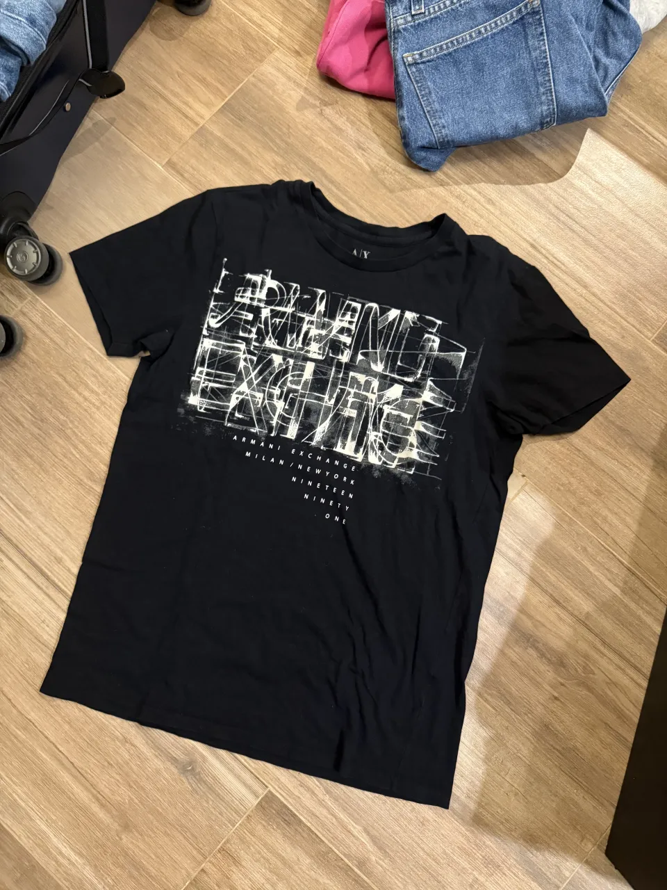 Remera negra de manga corta con estampa gráfica blanca en el frente. La estampa incluye texto y formas abstractas.