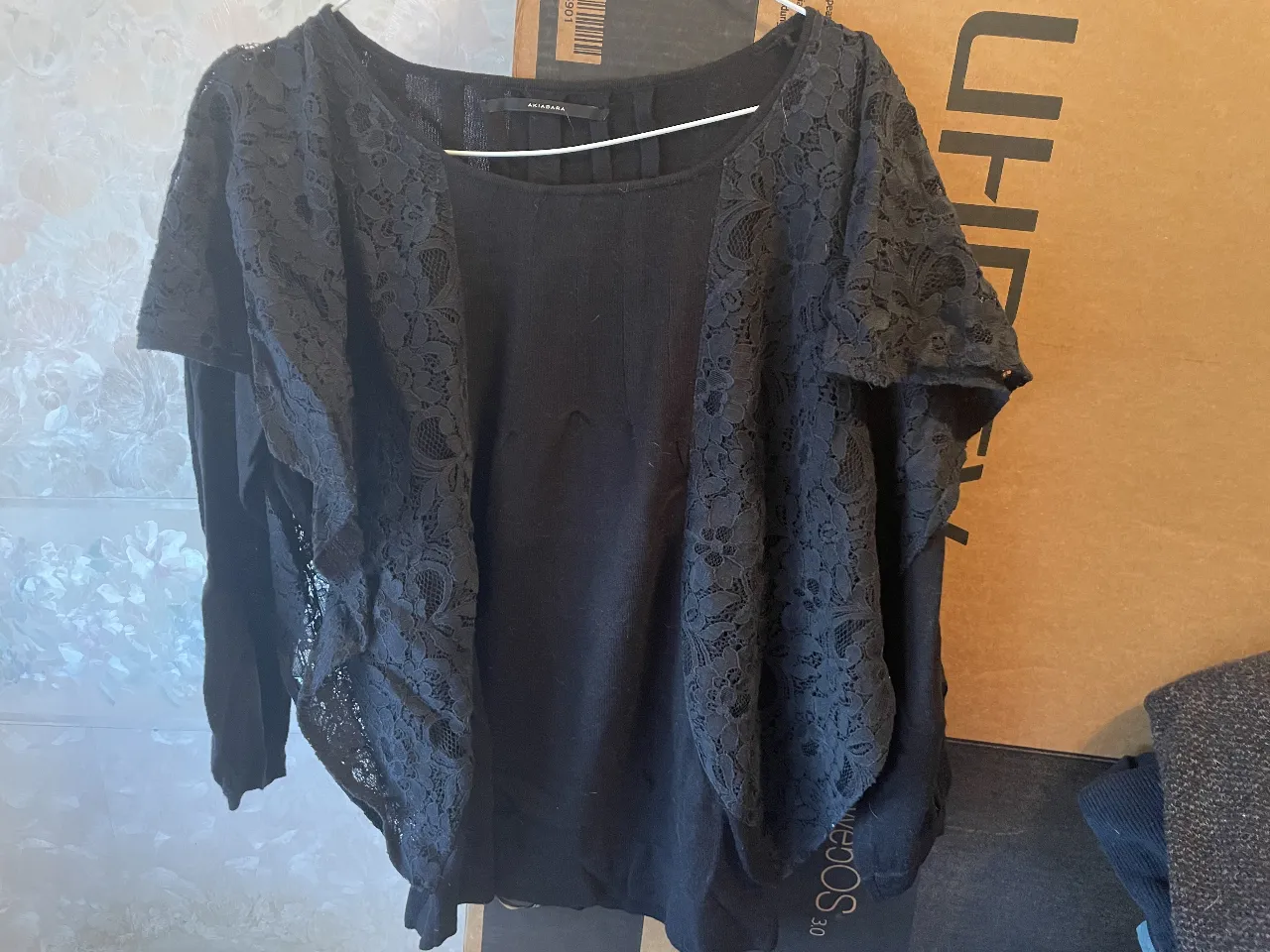 Sweater negro con detalles de encaje en los laterales, ideal para un look elegante y sofisticado. Perfecto para combinar con pantalones de vestir o faldas.