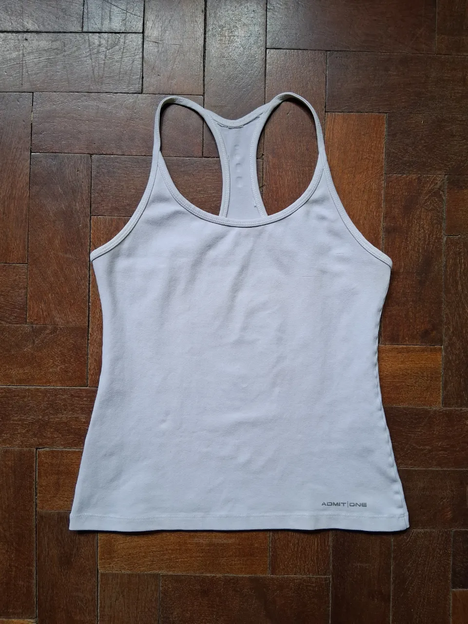 Musculosa deportiva gris clara, ideal para entrenar o para un look casual y cómodo. Marca Admit One. Talle 1. Medidas: axila a axila 35 cm, largo 50 cm. Es elastizada.