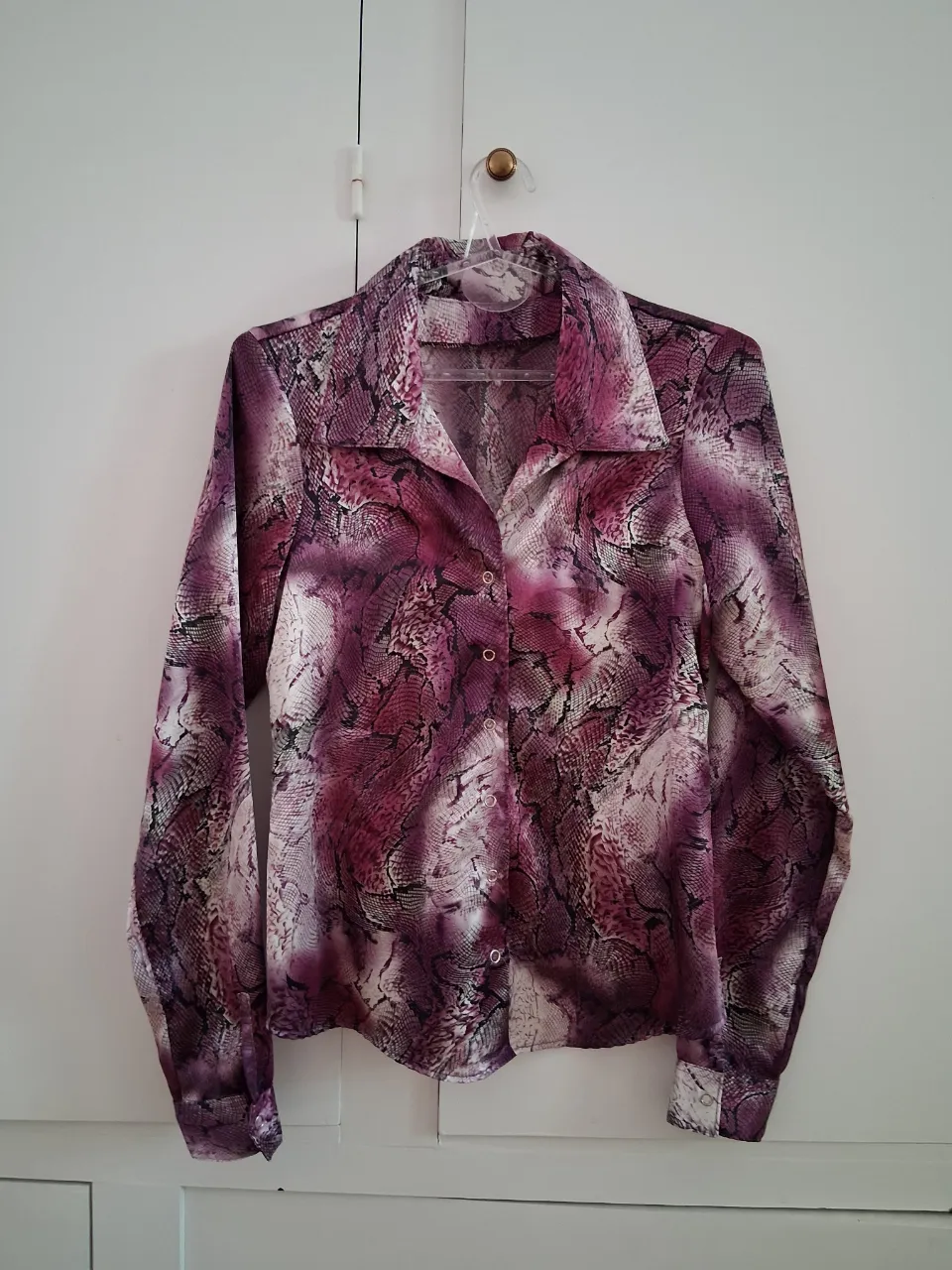 Camisa animal print serpiente en tonos fucsia, blanco y negro. Botones a presión. Talle S. Medidas: axila a axila 45 cm, hombro a hombro 37 cm, largo 60 cm, largo de manga 65 cm.