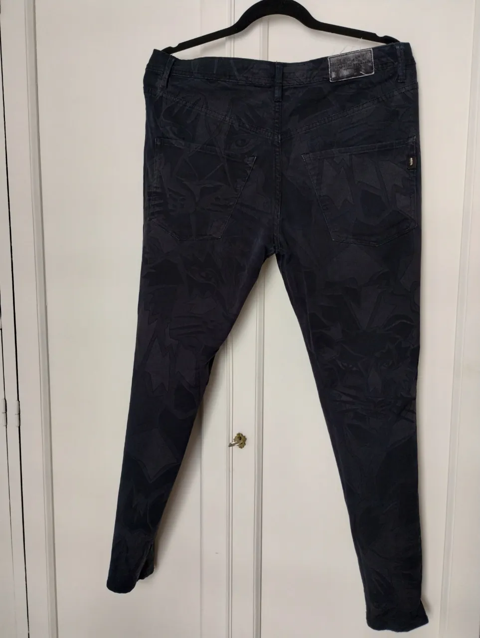 Jeans negros con estampa abstracta de felinos y labios rojos en el interior. Tiro largo como babucha bien chupin abajo