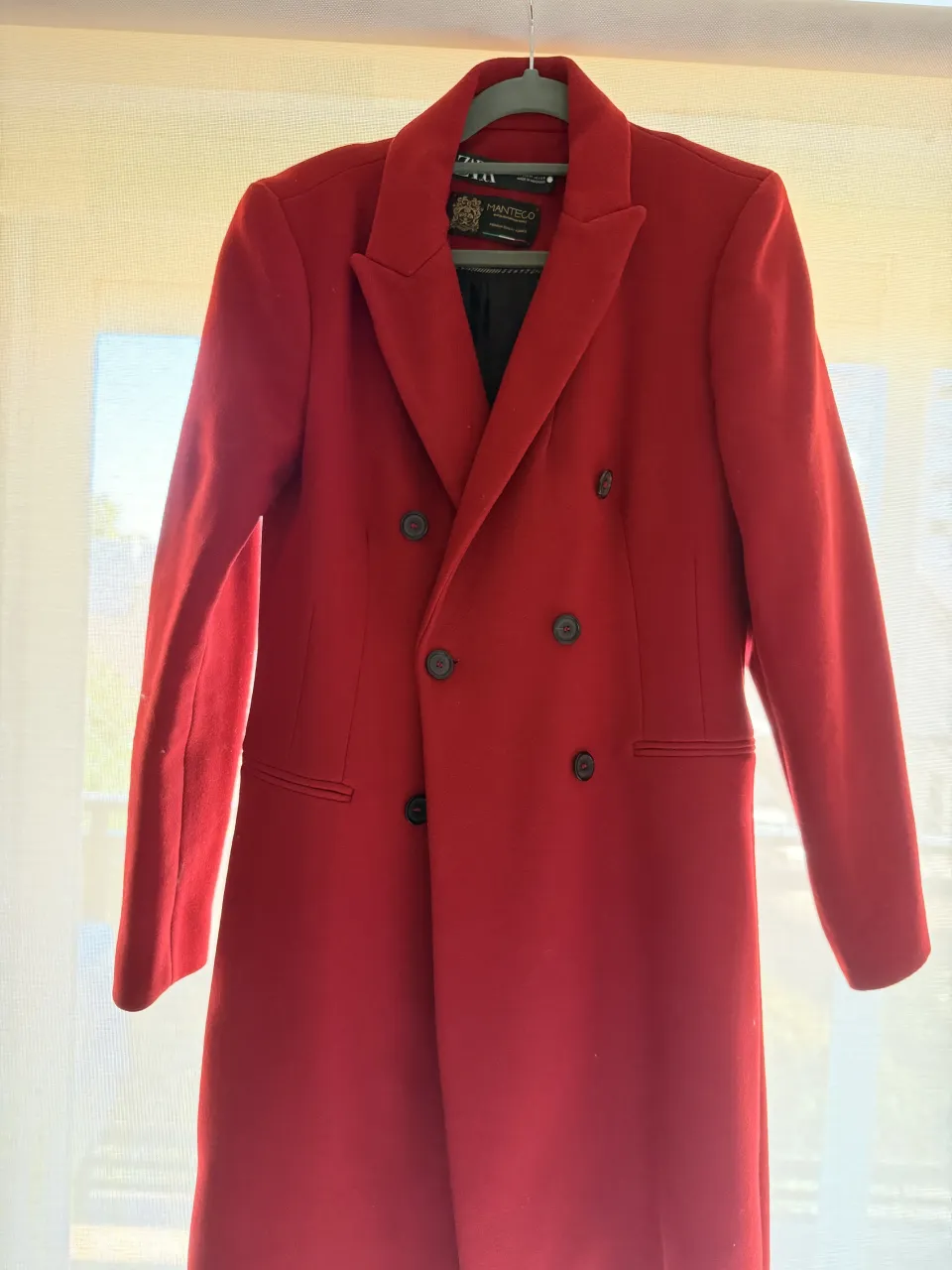 Tapado largo de paño color rojo es de la coleccion MANTECO con doble abotonadura y cuello solapa. Posee cuatro botones en cada puño.