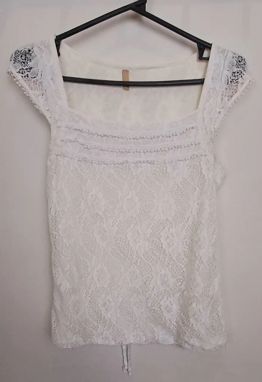Blusa de encaje blanca, con escote cuadrado y detalle de volados. Ideal para un look romántico y elegante.