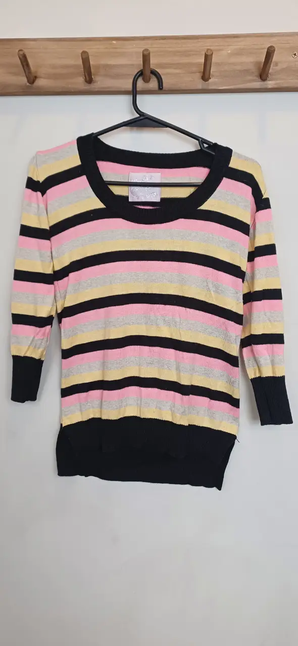 Sweater a rayas horizontales en tonos rosa, negro, amarillo y gris. Cuello redondo y mangas 3/4. 