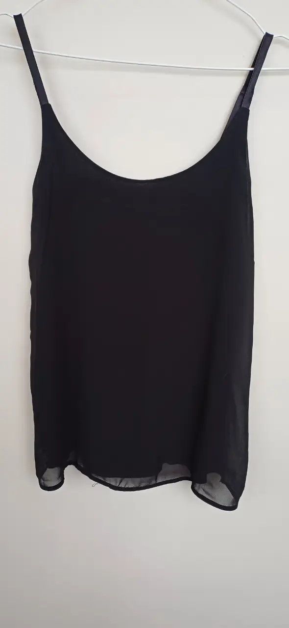 Top negro de tirantes finos, ideal para combinar con diferentes outfits. Perfecto para un look casual o para usar debajo de otras prendas.