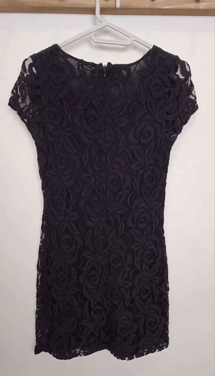 Vestido mini de encaje negro, ideal para fiesta o salida. Diseño ajustado con mangas cortas y cierre trasero.