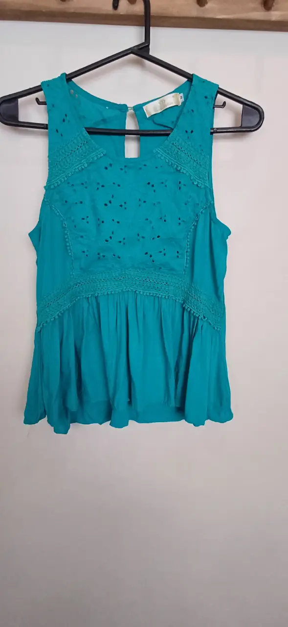 Blusa turquesa con detalles calados y volados. Ideal para un look fresco y femenino.