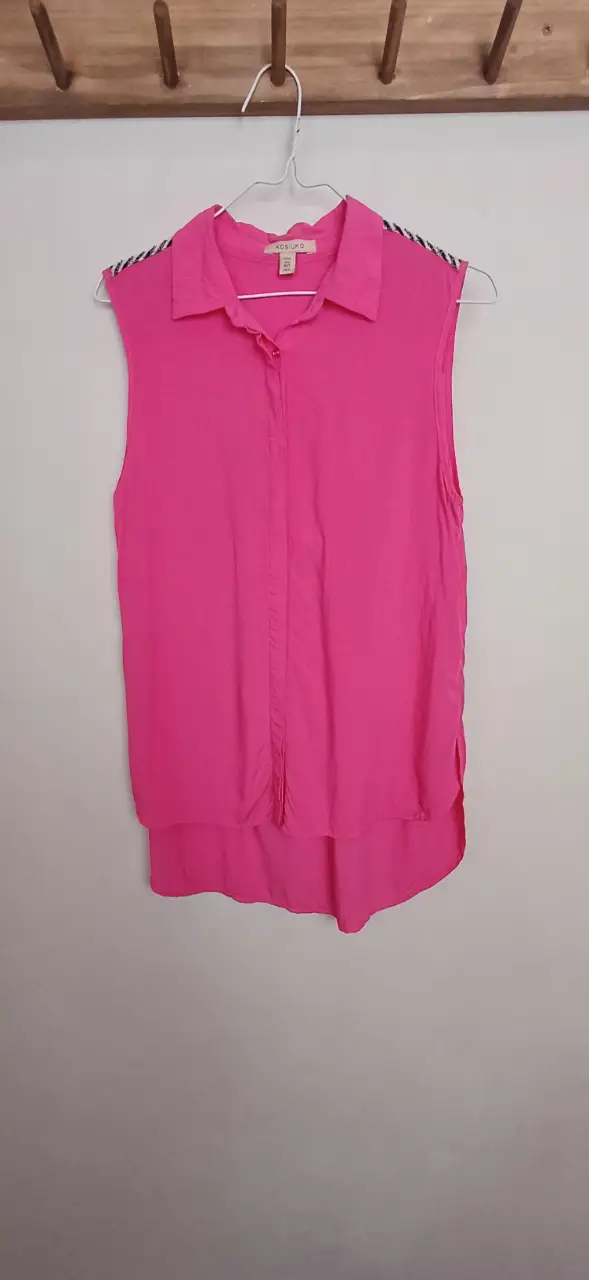 Blusa sin mangas de color rosa, con detalles en los hombros en blanco y negro. Ideal para un look casual y fresco.