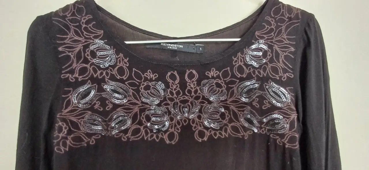 Blusa negra con detalles bordados en el frente. Manga 3/4 y cuello redondo. Ideal para un look elegante y sofisticado.