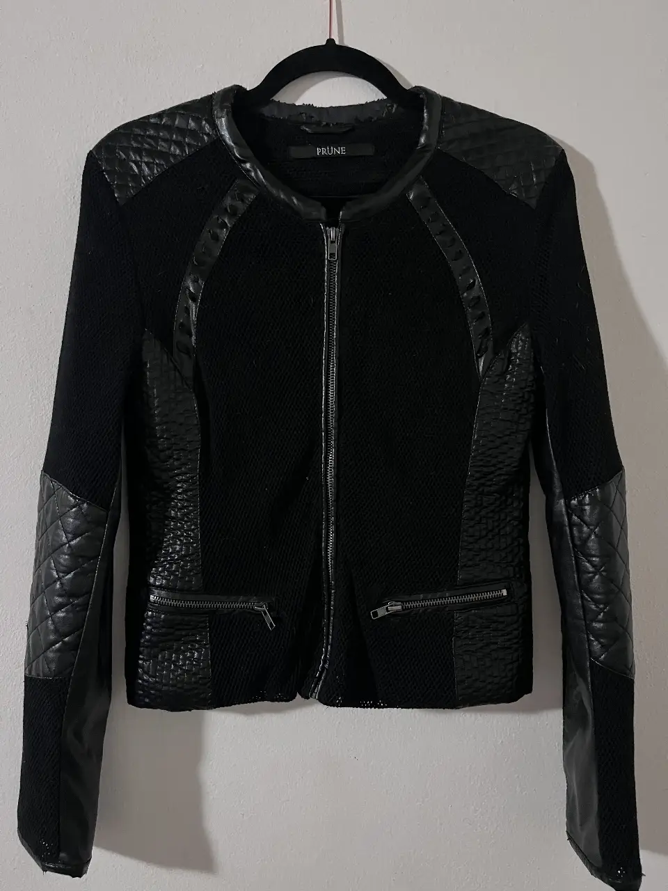 Campera negra de mujer, con detalles en cuero sintético y diseño con costuras en mangas y hombros. Cierre frontal y bolsillos con cremallera. Dice talle 40 (va para S). Tiene desgastes en el cuello.